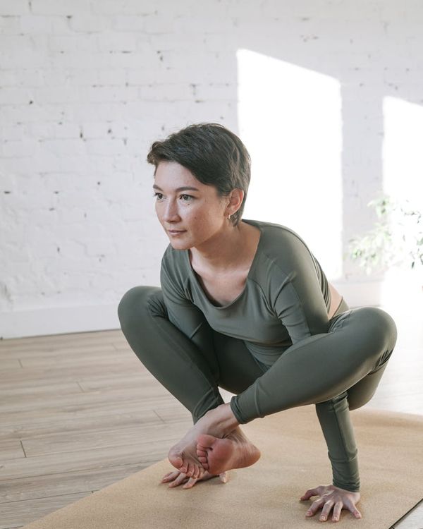 Woman in a calm, stretching pose in a bright room.